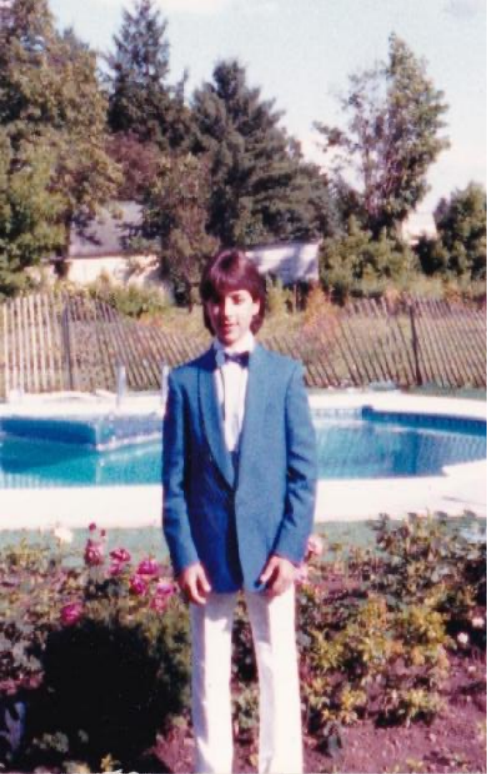 John Petrelli as a young student, wearing a blue jacket and bow tie outdoors